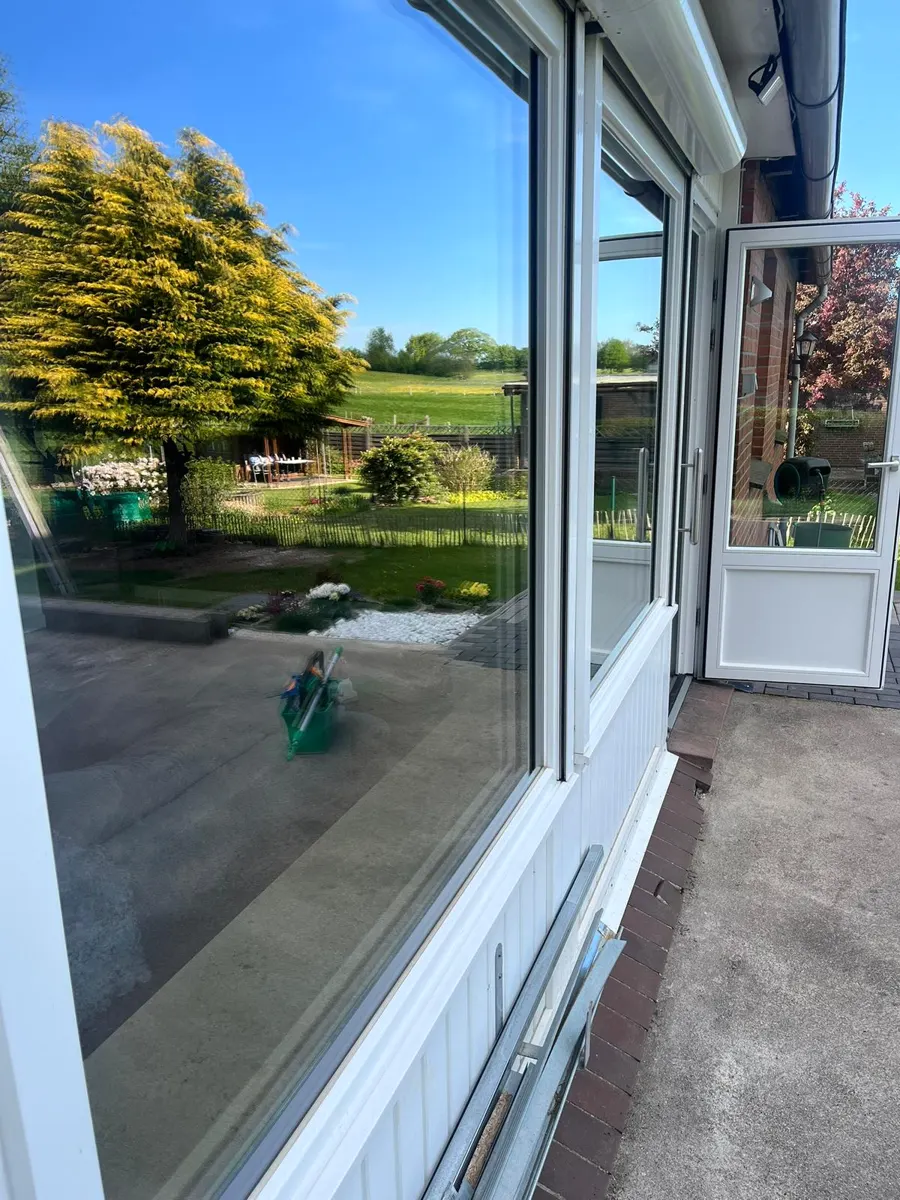 Frisch geputzte Fensterfront mit Spiegelung von Garten und Himmel